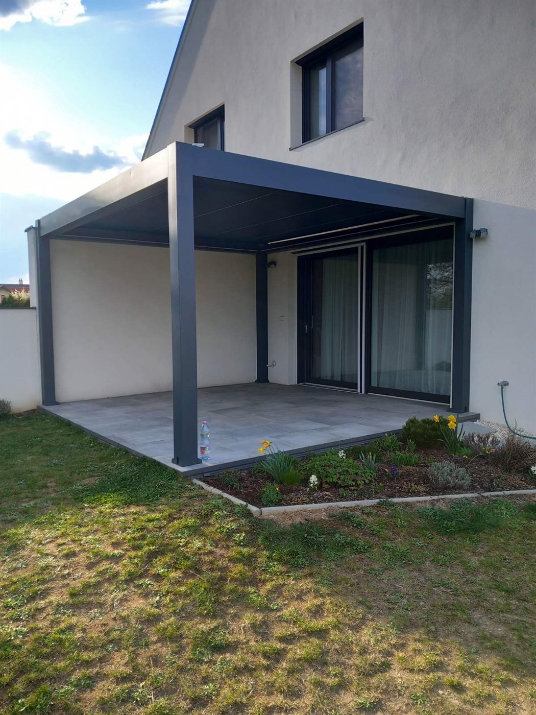 Antracit pergola családi ház teraszán, tolóajtós nappalival