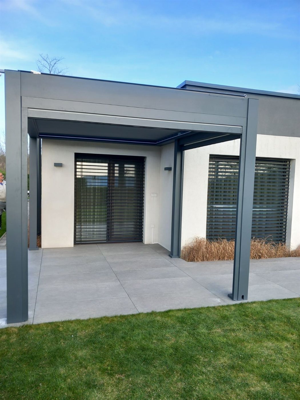 Antracit pergola modern ház sarkán, kék ég alatt