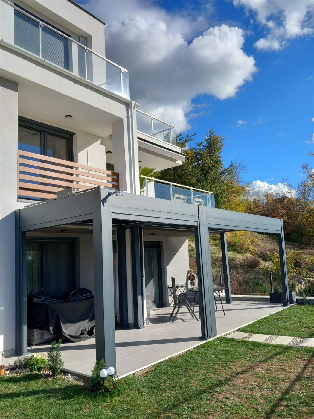 Hosszú antracit pergola modern ház teraszán, dombos háttérrel